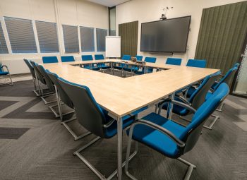 The conference room interior of a modern office with white walls and a monitor